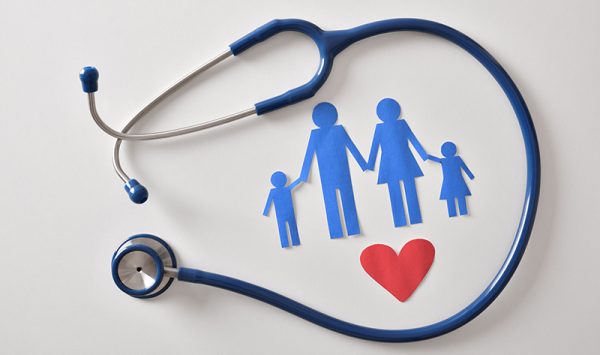 Concept of family medicine with ostetoscope and paper cut of family and heart on a white table. Top view. Horizontal composition.